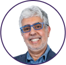 Smiling older man with gray hair, a short beard, blue glasses, and a blue shirt with a blazer, shown in a circular frame on a white background—perfect for Cybericon2024 profiles.